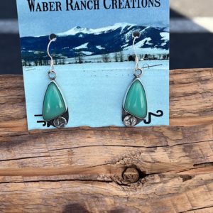 Green earrings on a wooden table.