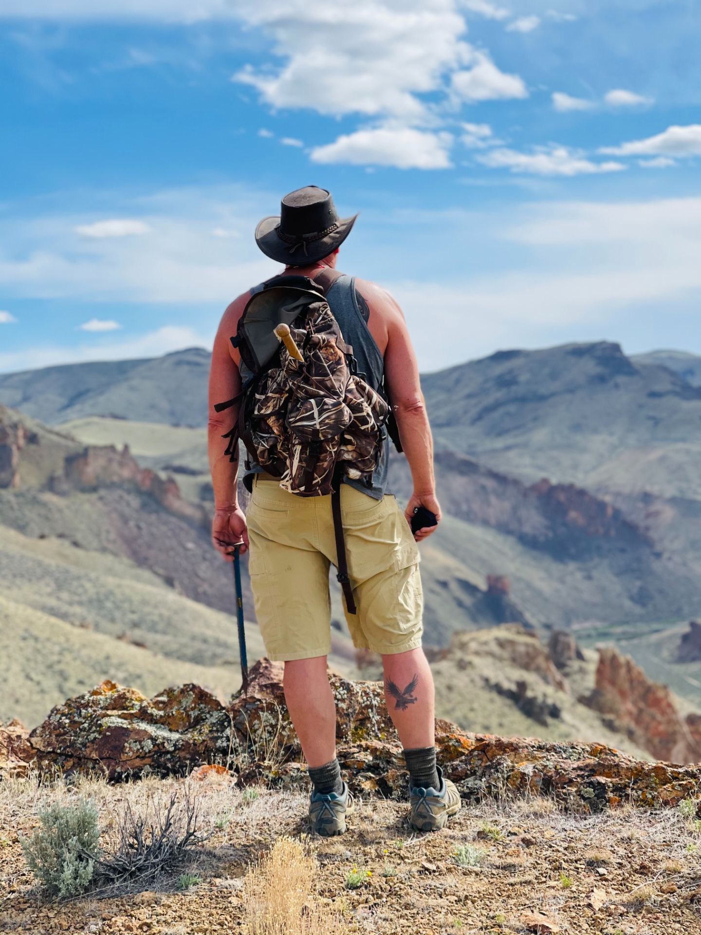 Man wearing a hat standing on top of a mountain.